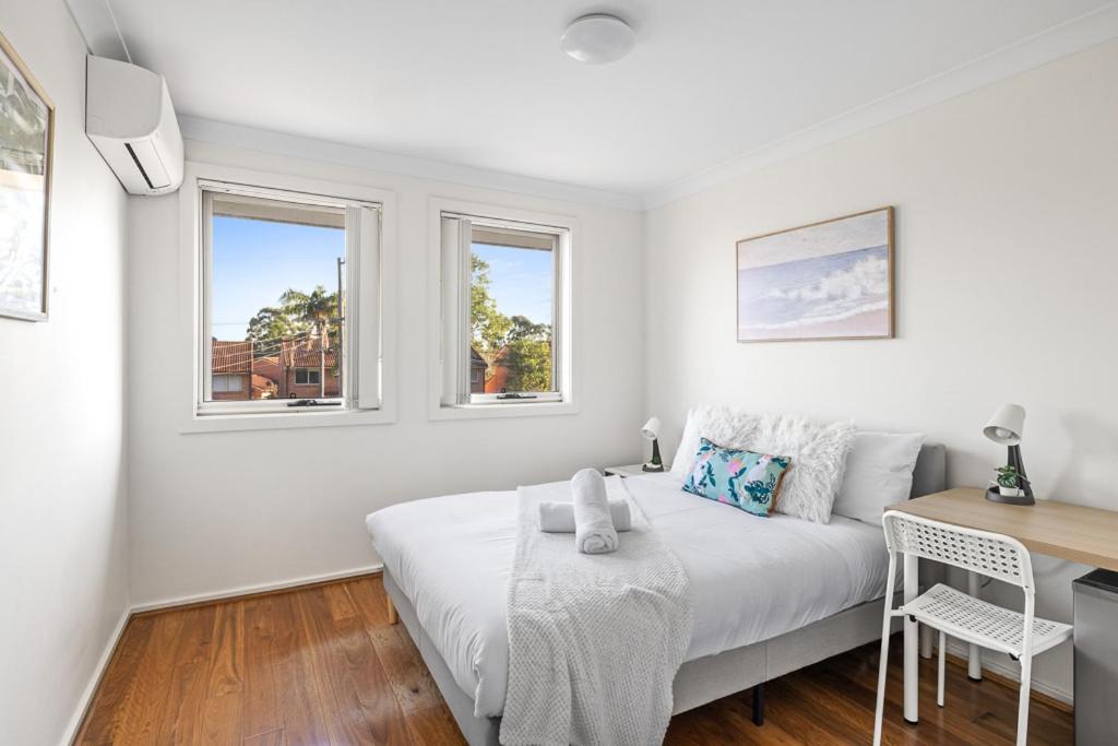 a white room with a bed and a desk and windows at Luxe Double Room in Panania - Nearby Stations & Shops - Shared Bathroom in Panania