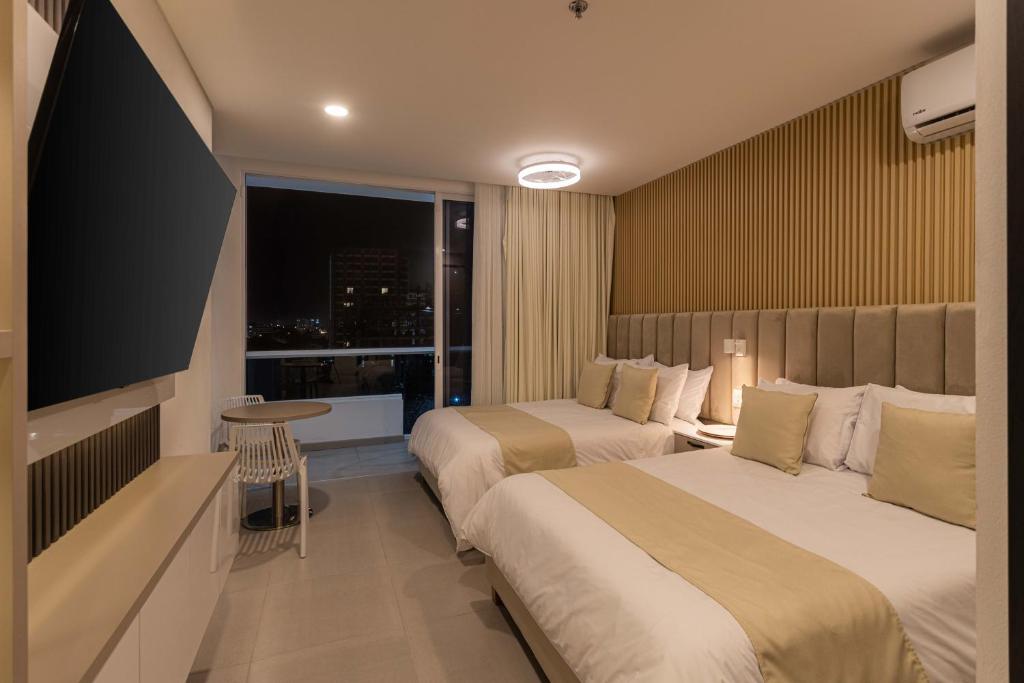 a hotel room with two beds and a large window at Aparta suite Playa Bello Horizonte Santa Marta in Santa Marta