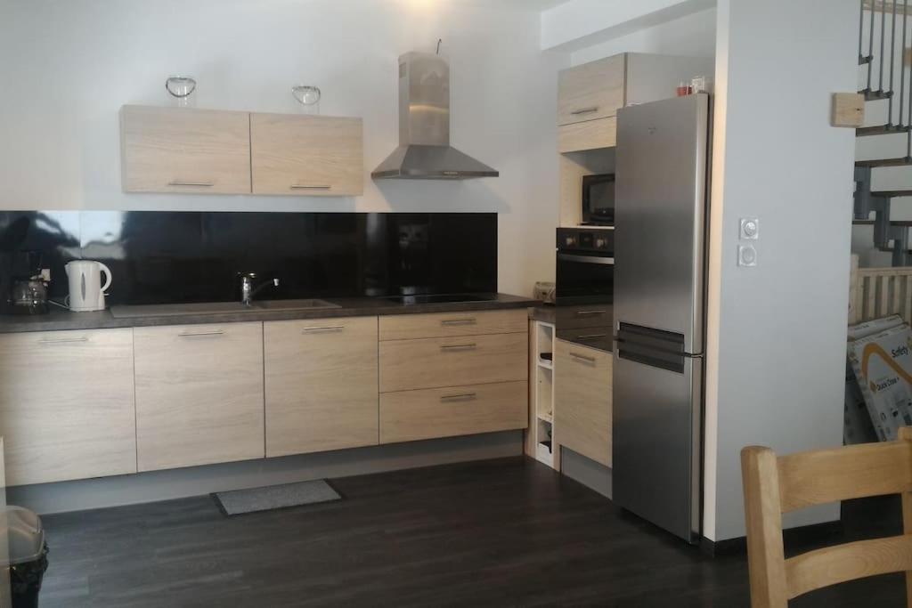 eine Küche mit Holzschränken und einem Edelstahlkühlschrank in der Unterkunft Chalet Au Cottage des Lynx in Xonrupt-Longemer