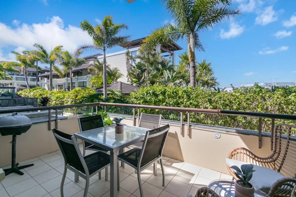 a balcony with a table and chairs and palm trees at 105 Santai - Ground Floor Studio Apartment by uHoliday in Casuarina