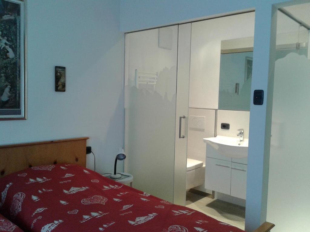 a bedroom with a bed and a bathroom with a sink at Condominio Zorzi in Moena