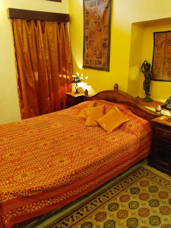 a bedroom with a bed with an orange comforter at Killa Bhawan Lodge in Jaisalmer