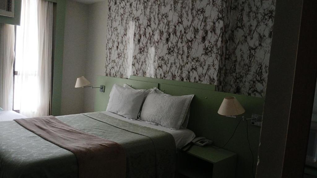 een slaapkamer met een bed en een schilderij aan de muur bij comfort hotel 413 anfitriã in Taguatinga