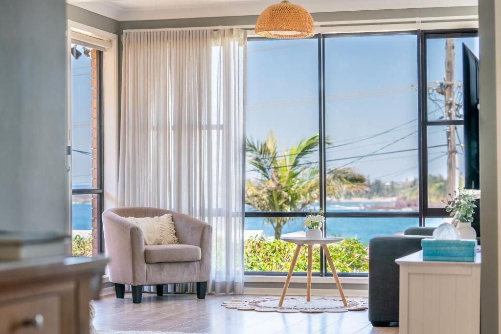a living room with a couch and a chair and a large window at Spectacular Ocean View Home in Bombo in Kiama Downs