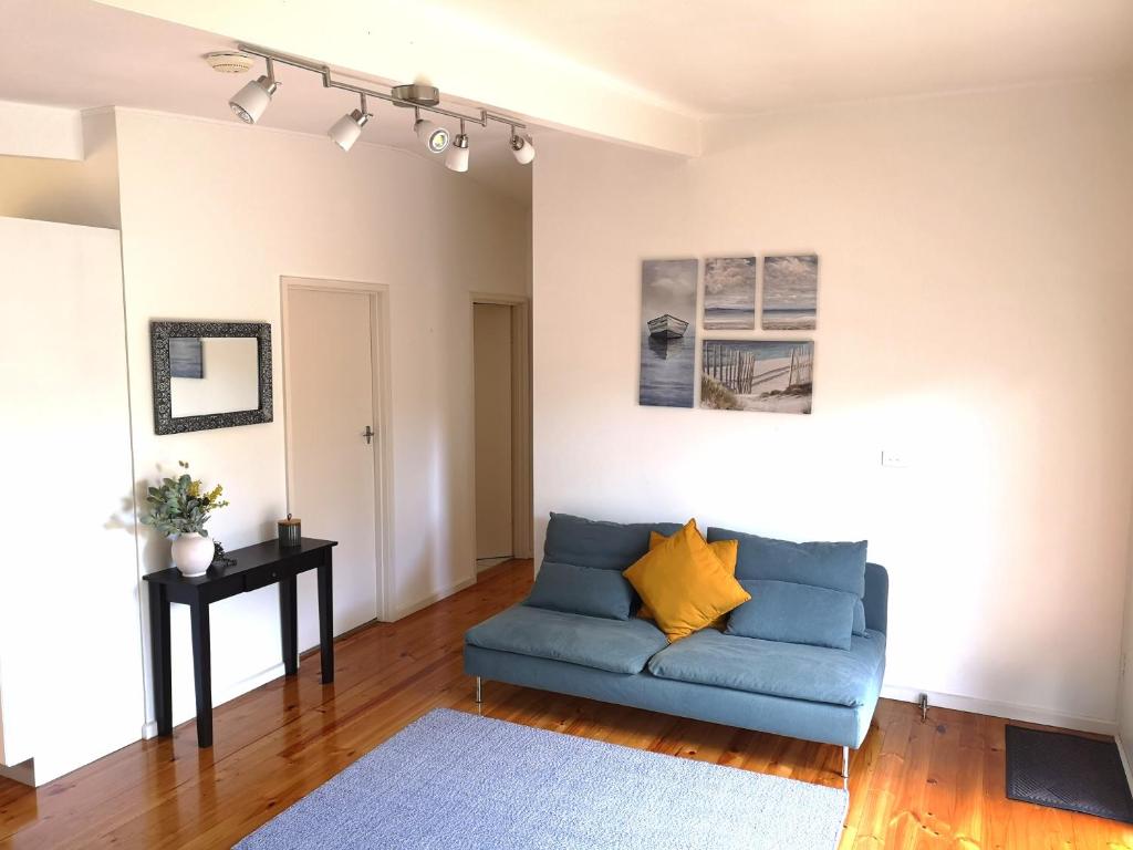 a living room with a blue couch and a table at Rye Holiday Getaway BYO Linen and Towels 750m walk to Beach in Rye