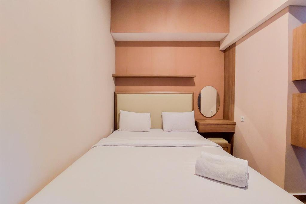 a bedroom with a white bed with a mirror at Homey and Modern 2BR at Casa de Parco Apartment By Travelio in Tangerang