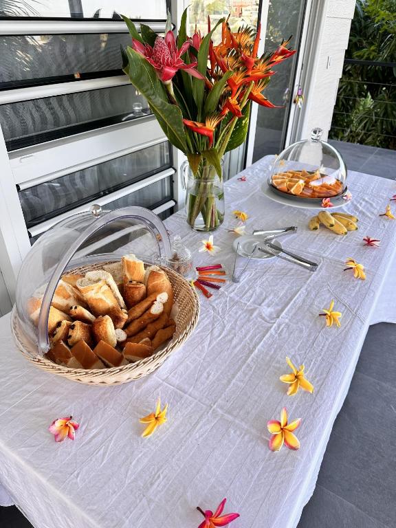 a table with a basket of bread and a vase of flowers at Ononui Lodge Airport, Ocean-View, Private Bathroom and Balcony, Free WiFi and Parking, On-Site Car Rental in Faaa
