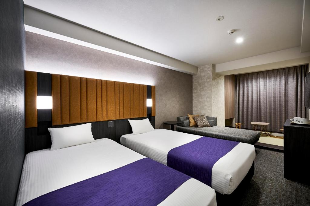 a hotel room with two beds and a couch at hotel MONday KYOTO MARUTAMACHI in Kyoto