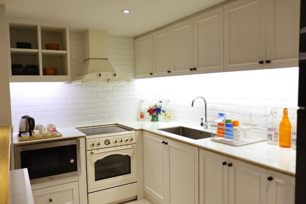 A fully fitted kitchen with cabinets, oven, cooktop, sink, kettle, and refrigerator.