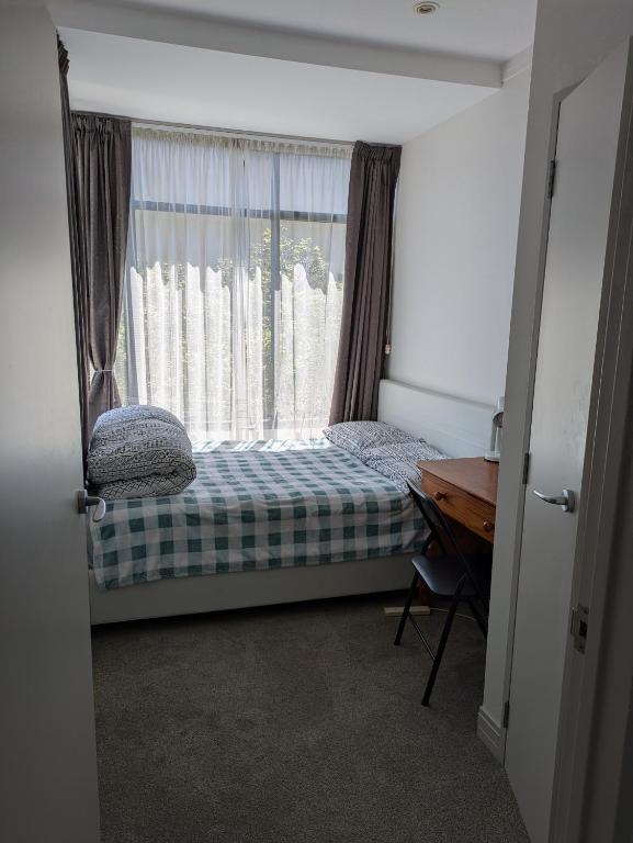 mała sypialnia z łóżkiem i oknem w obiekcie Newmarket Homestay - Double Room w Auckland