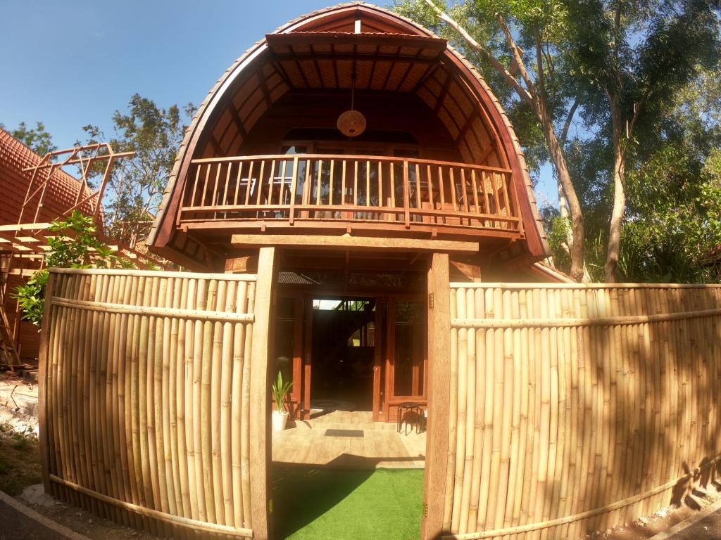 a wooden building with a balcony on top of a yard at 2 storey wooden house in the heart of Uluwatu in Uluwatu
