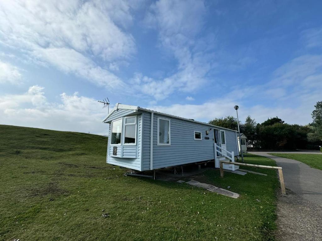 una piccola casa blu in cima a un campo di Family Beach Getaway, Pools, Mountains and more a Prestatyn