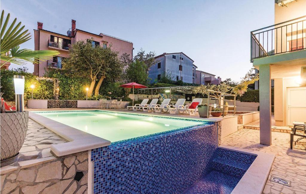 a swimming pool in a yard with chairs and a building at 1 Bedroom Amazing Apartment In Banjole in Banjole