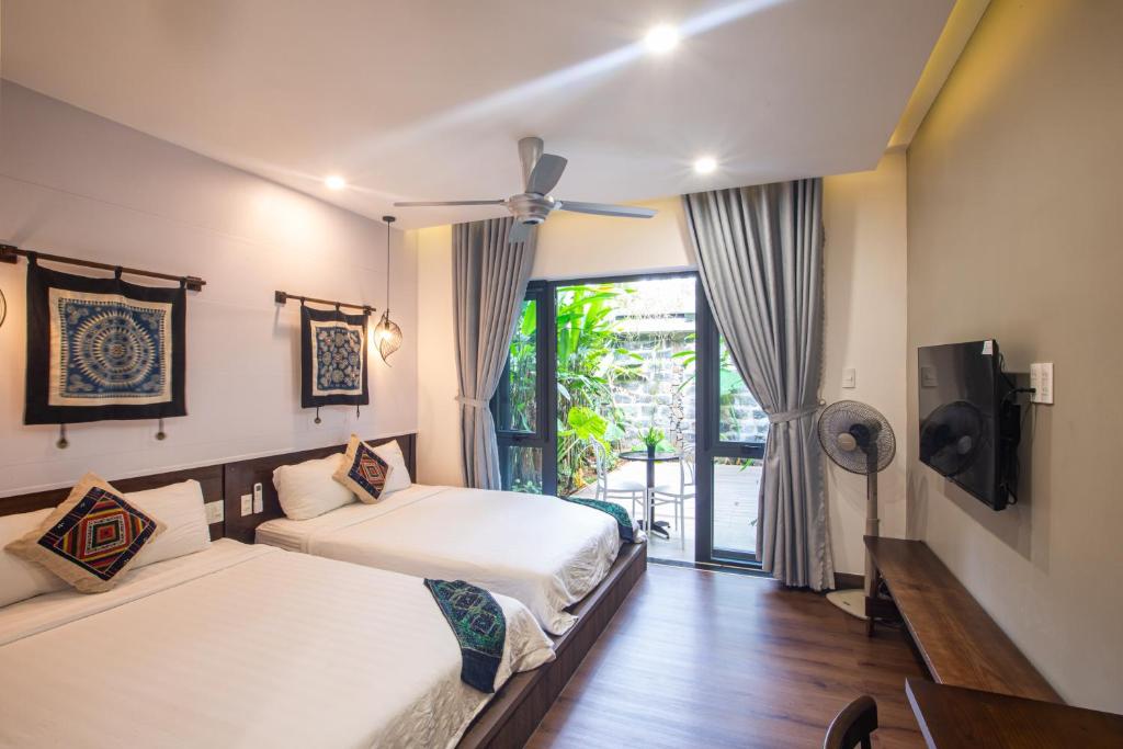 a bedroom with two beds and a sliding glass door at Casa Vanilla Mang Den in Kon Von Kla