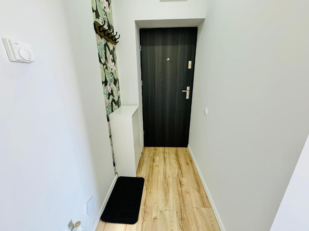 a hallway with a black door and a wooden floor at Przy Parku Róż II in Chorzów