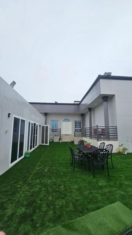 une terrasse avec une table et des chaises sur une pelouse dans l'établissement استراحة الهولي, à Ma‘mūrah