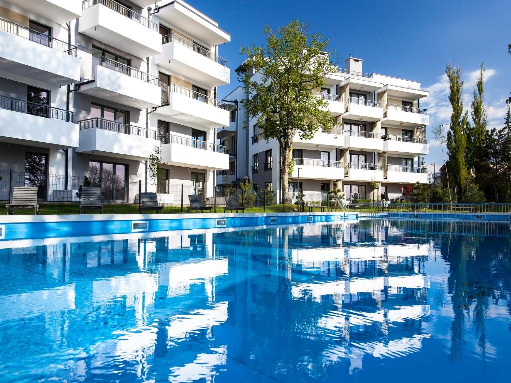 a swimming pool in front of a building at Equilibrium Apartments in Ustronie Morskie