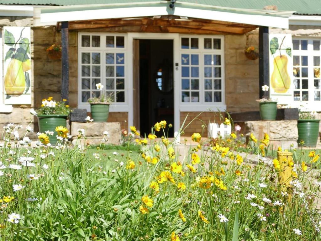 a garden with flowers in front of a house at Peerboom Guesthouse in Fouriesburg