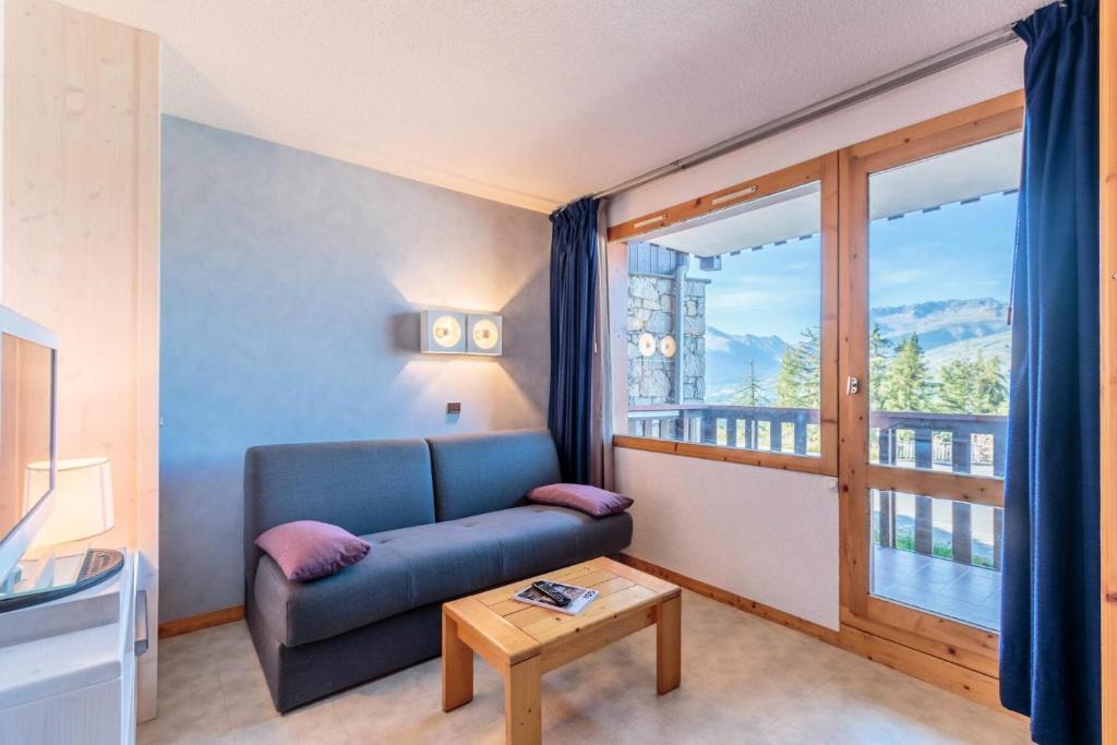 un salon avec un canapé bleu et une fenêtre dans l'établissement Résidence La Traverse - TRAVERSE 06 MAE-0751, à La Plagne Tarentaise