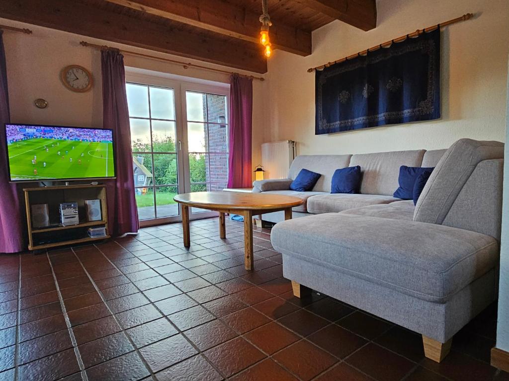 a living room with a couch and a table and a tv at Ferienhaus Seewiefken in Hooksiel