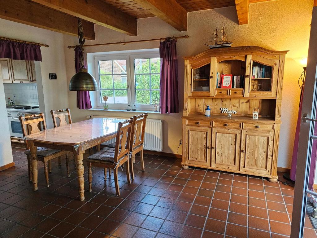 cocina con mesa de madera, sillas y ventana en Ferienhaus Seewiefken, en Hooksiel