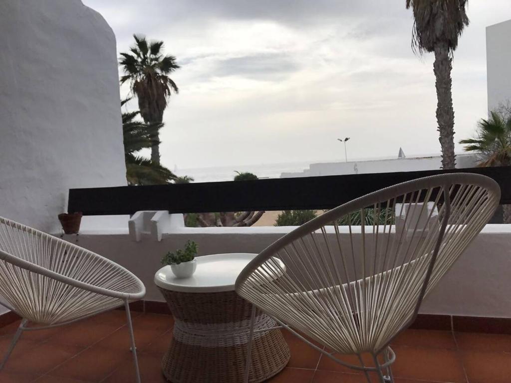 dwa krzesła i stół na balkonie z palmami w obiekcie La playita, primera linea de mar w Puerto del Carmen