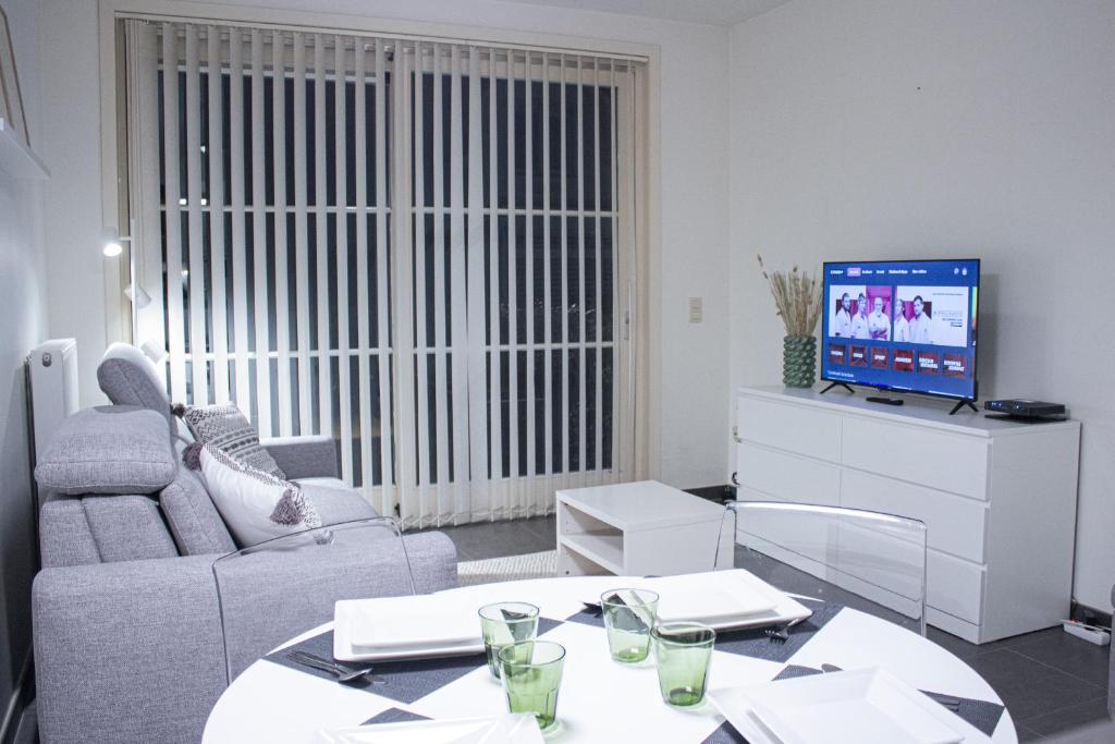 a living room with a couch and a tv at Appart avec terrasse proche mer in De Panne