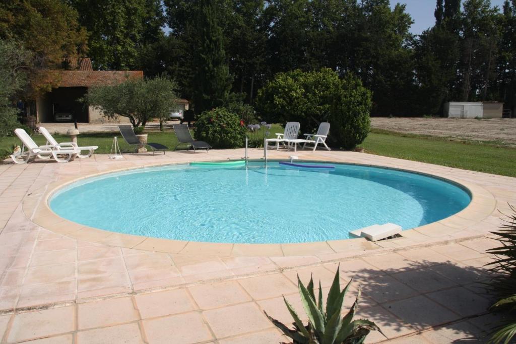 - une grande piscine avec des chaises et une table dans la cour dans l'établissement Le Mas des Cigales, à Avignon