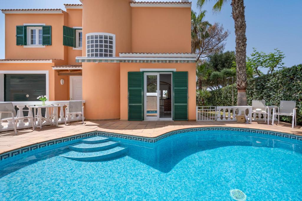 a villa with a swimming pool in front of a house at Villa Cristina in Cala Blanca