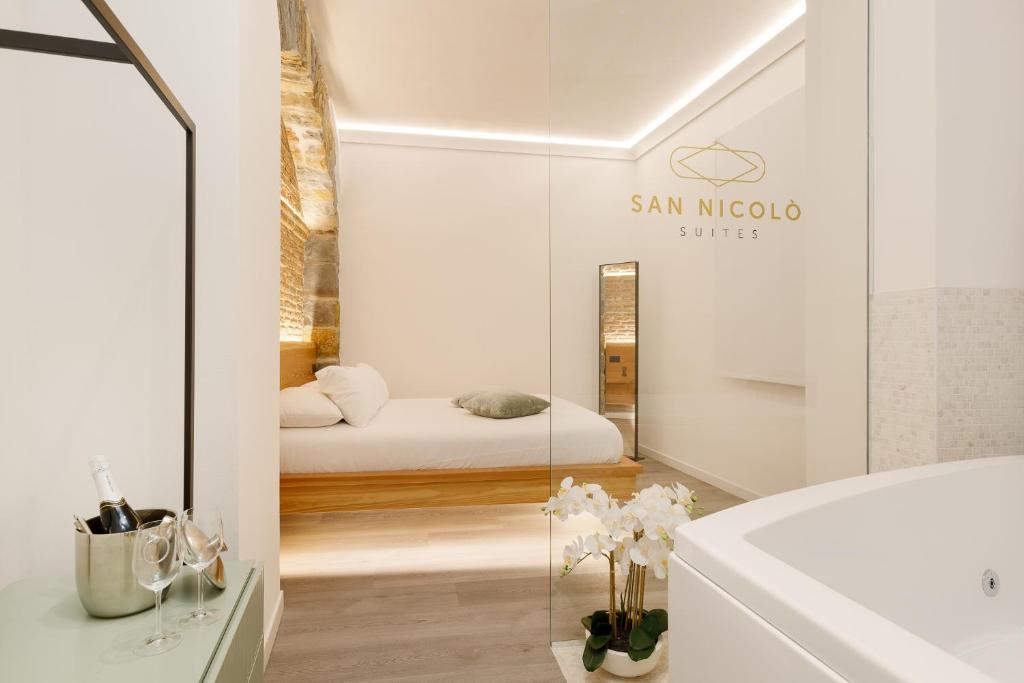 a white bathroom with a bed in the background at San Nicolò Suites in Trieste