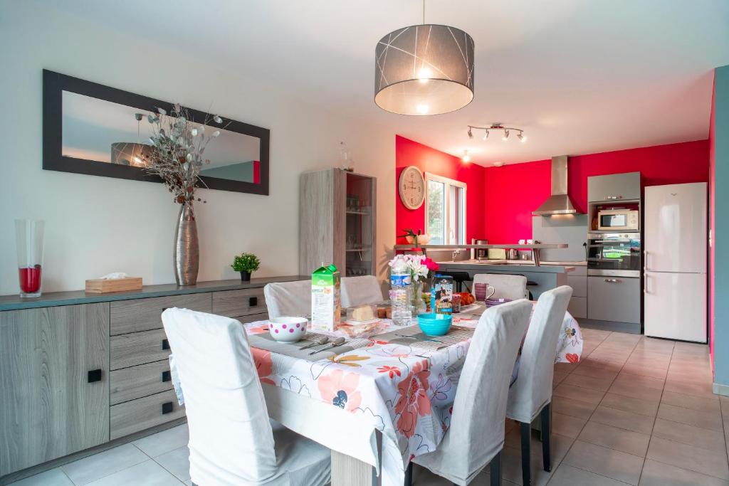 - une cuisine avec une table, des chaises blanches et des murs rouges dans l'établissement La Villa de l'Odet - 4 Chambres et parking privé, à Pleuven