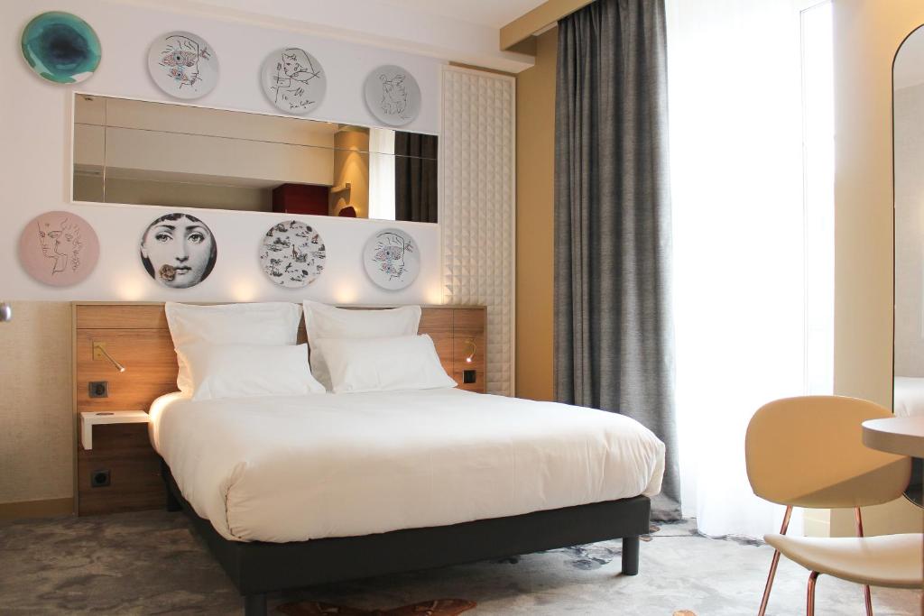 Un dormitorio con una cama grande con almohadas blancas. en Brit Hotel Limoges Centre Gare - Hôtel &amp; Spa, en Limoges