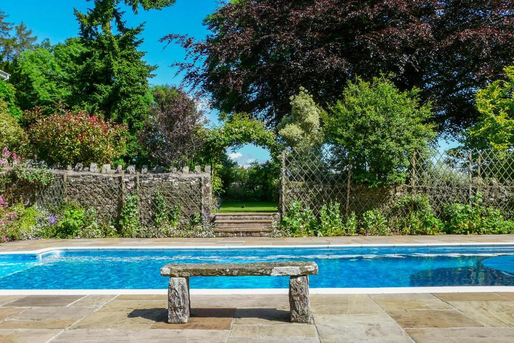 a stone bench sitting next to a swimming pool at Buckstone House Coach House in Coleford
