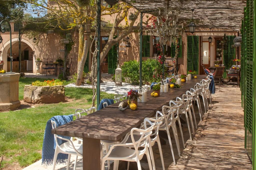 une longue table en bois avec des chaises blanches autour dans l'établissement Suite Xaloc im Es Llobets, à Llucmajor
