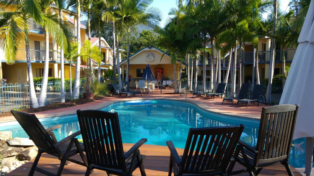 uma piscina com cadeiras de baloiço e palmeiras em at Beach Court Holiday Villas em Airlie Beach