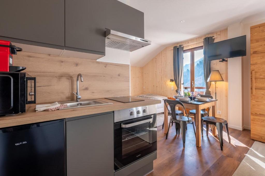 a kitchen with a sink and a table with chairs at Le Petit Aravis - village et vue panoramique in La Giettaz