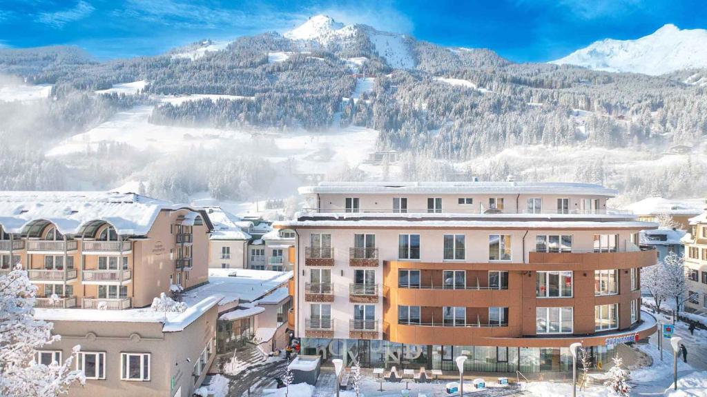 een groep gebouwen in de sneeuw voor een berg bij Aktiv- & Gesundheitsresort das GXUND - Thermeneintritt inklusive in Bad Hofgastein