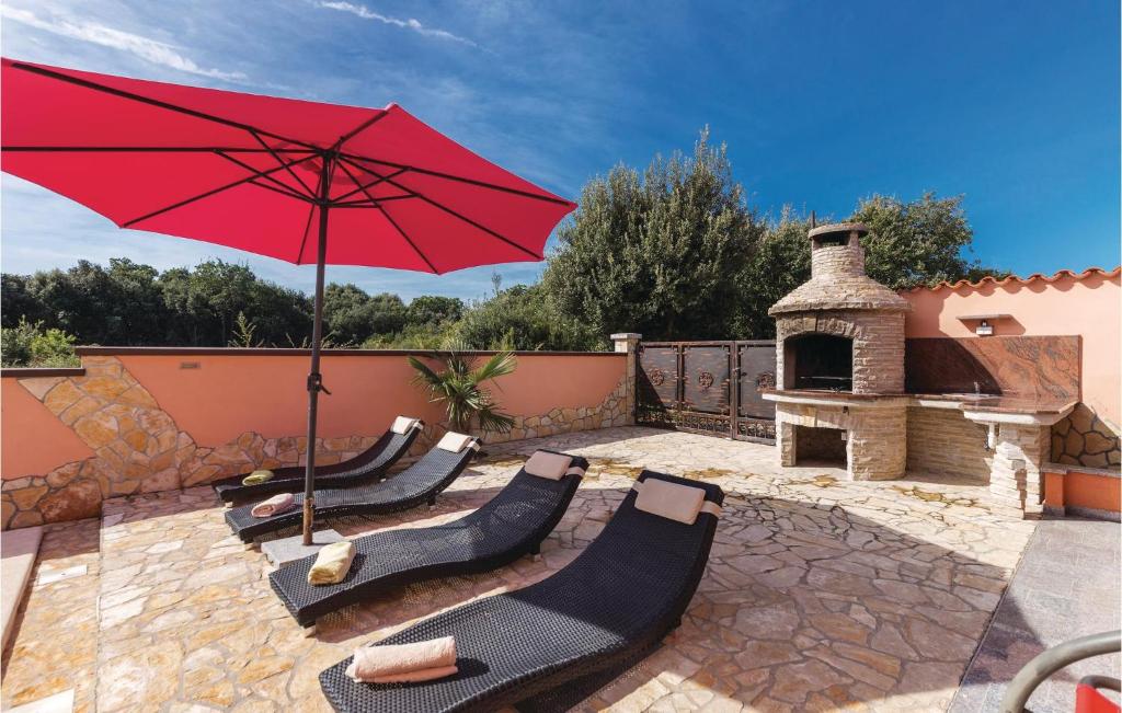 patio z czerwonym parasolem i krzesłami oraz sprzętem do grillowania w obiekcie Holiday Home Betiga Betiga Ii w mieście Barbariga