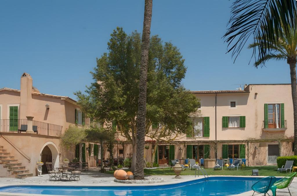 un complexe avec une piscine, des palmiers et un bâtiment dans l'établissement Suite Mestral im Es Llobets, à Llucmajor