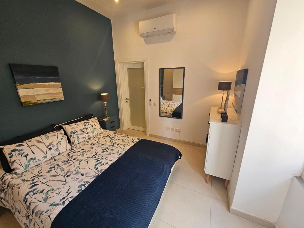 a bedroom with a bed with a blue and white comforter at Maltese Coastal Escape in Sliema