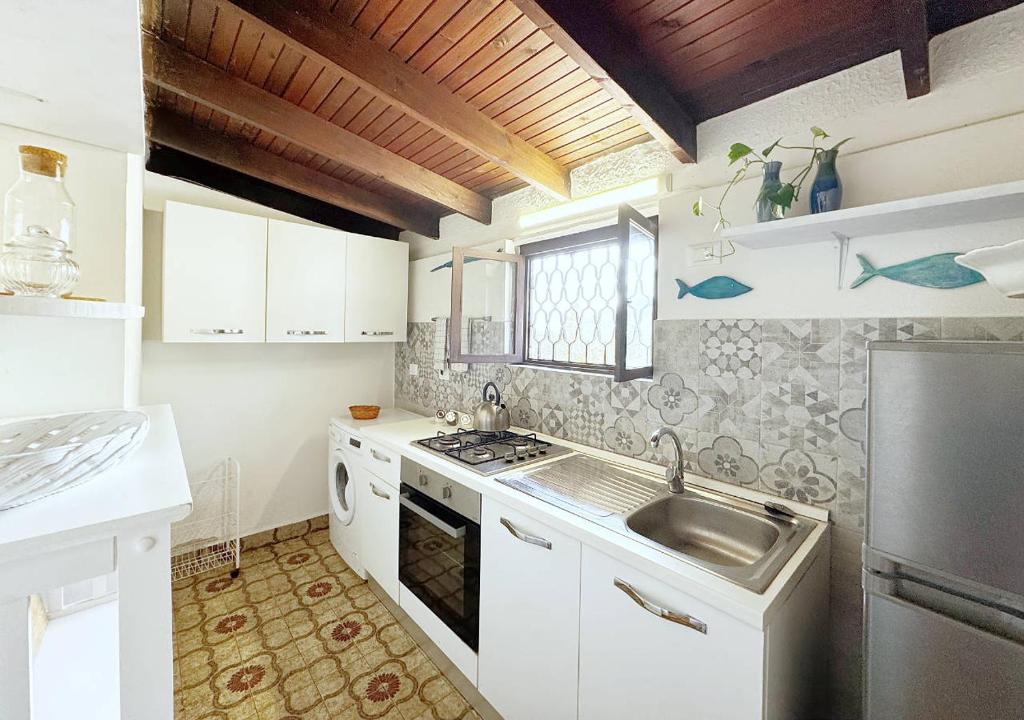 Biała kuchnia ze zlewem i kuchenką w obiekcie Solemar Sicilia - Seaside House Capo Zafferano w mieście Santa Flavia