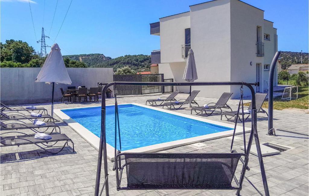 a swimming pool with chairs and an umbrella next to a house at Cozy Home In Rab With Wifi in Rab