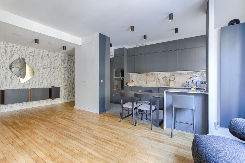 Il comprend une cuisine avec des placards gris et du parquet. dans l'établissement Luxury apartment at heart of Paris, à Paris