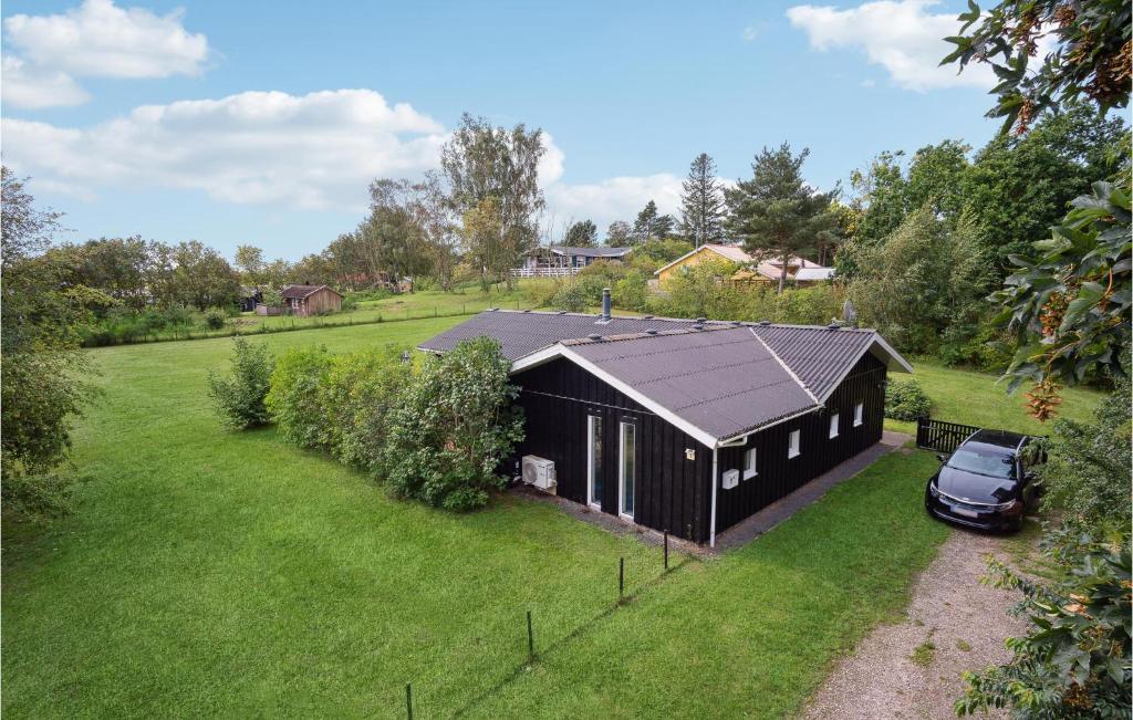 a black house with a car parked in a field at Pet Friendly Home In Knebel With Sauna in Skødshoved Strand