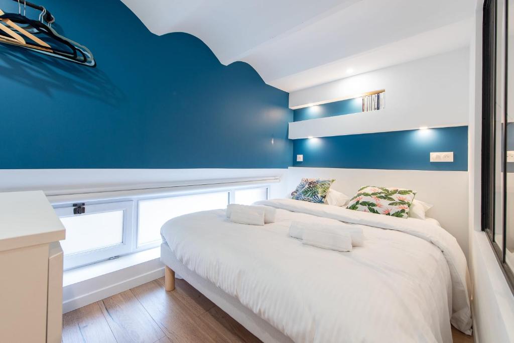 sypialnia z białym łóżkiem i niebieską ścianą w obiekcie LE CHANCEUX fabuleux duplex en design, pour loisir en couple ou congrès w Cannes