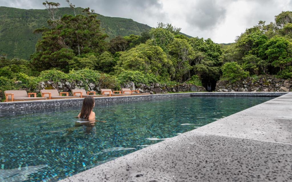 a woman sitting in the water in a swimming pool at Aldeia da Cuada in Faja Grande