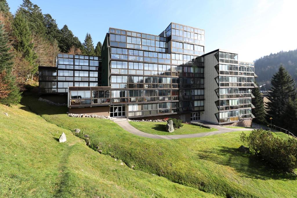 un grand bâtiment sur une colline avec un champ verdoyant dans l'établissement Le ptit vosgien - Appt à 15min des pistes, à La Bresse