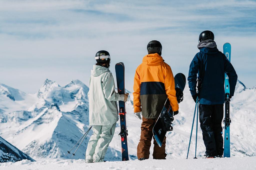 three people standing on top of a mountain with snowboards at Sunshine in Saas-Grund