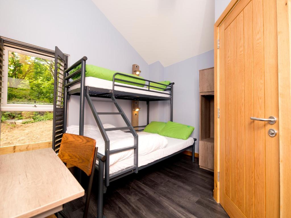 a bedroom with bunk beds and a table and a door at YHA Boggle Hole in Fylingthorpe