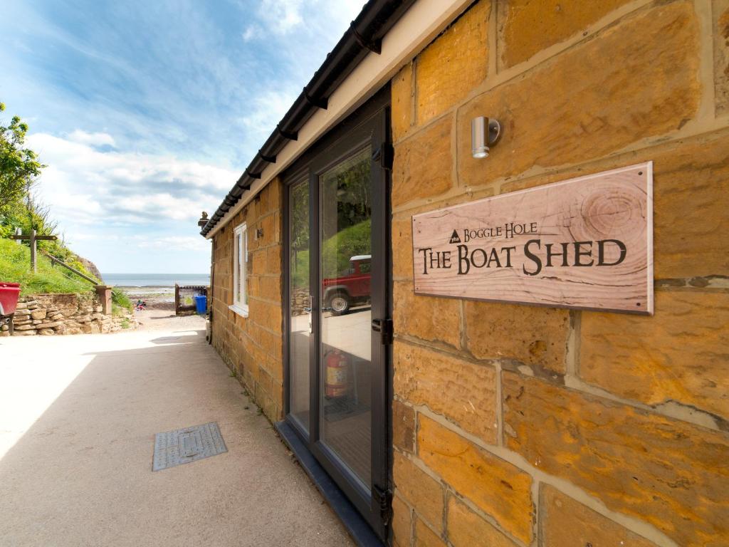 a brick building with a sign that reads the boat shed at YHA Boggle Hole in Fylingthorpe